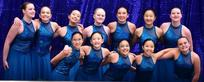 Triangle Synchro Pre-Juvenile team, 12 skaters posing together in blue sequined costumes